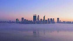 Aerial footage of fog on the Swan River as the dawn light breaks over the horizon behind the Perth City skyline.